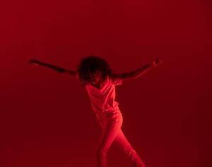 red lights on stage modern dancer arms out