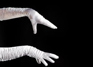 two arms reaching with white gloves are in front of a black background