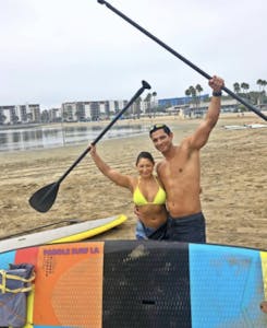 a couple that completed a paddleboard trip hugging and holding their paddles in the air with victory!