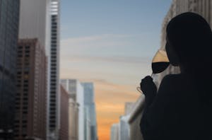 a lady sipping her wine looking at a view of chicago at sunset
