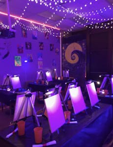 a purple light lighting up an art room with blank canvases ready for party guests