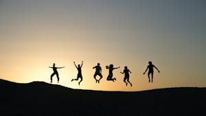 a group of people jumping in the sunset