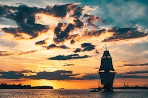 a landscape photo of a ship sailing at sunset
