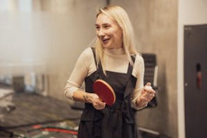 a blonde girl holding a red ping pong paddle