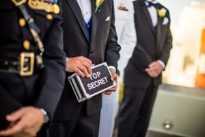 people in suits, one holding a box that says "top secret"