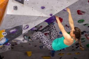 a girl bouldering on an indoor climbing wall