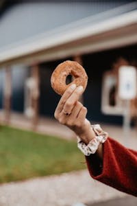 a person holding an apple cider donut