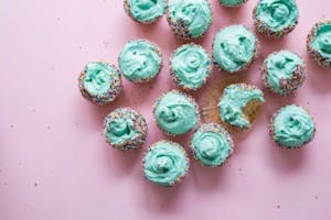 a group of cupcakes with green frosting and colorful sprinkles