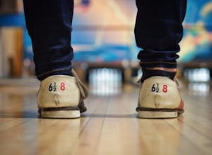 the back of bowling shoes standing by the bowling lane, with pins in the background