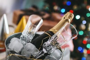 a bottle of champagne in a bucket in front of a christmas tree
