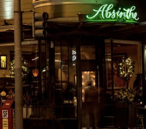The exterior of Absinthe restaurant in San Francisco with a green neon light sign