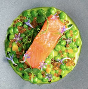 a close up of San Francisco Salmon plated over bright green veggies