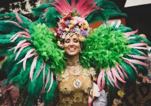 a lady in a colorful feather carnival outfit with green and pink