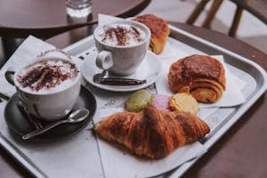 croissants and coffee with whipped cream on a serving tray