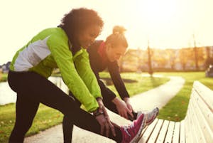 Women stretching on a bench before a run.
