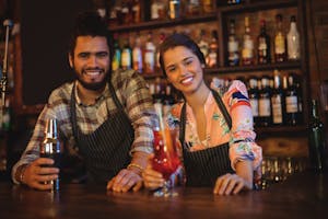 Portrait of happy waiter and waitress standing at counter