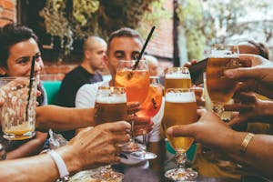 A group saying cheers with a bunch of different beers and cocktails