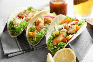 Stand with delicious fish tacos on table