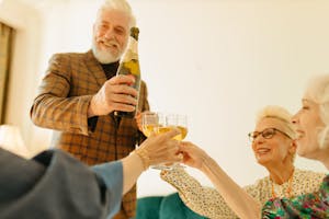 Man in Plaid Suit Jacket Holding Champagne Bottle with Others Clinking Their Glasses