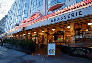 a brasserie from the exterior with a red neon sign