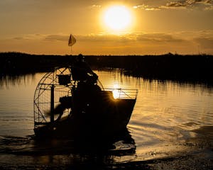 a sunset over a body of water with an airboat 