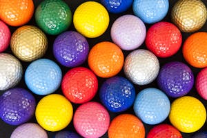 Colored golf balls - gold, green, blue, purple, orange, red, white, yellow, pink, and lavender