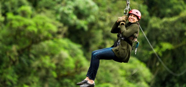 a woman on a zipline in a forest