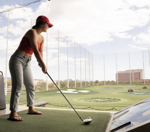 a woman wearing a baseball club holding a golf club