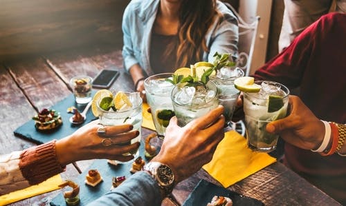 a group of people saying cheers with cocktails