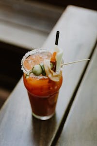 a glass cup with a bloody mary on a table