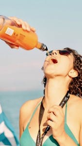 a girl wearing a bikini on a New Orleans party boat booze cruise has orange liqueur poured into her mouth
