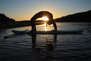 woman doing sup yoga during sunset