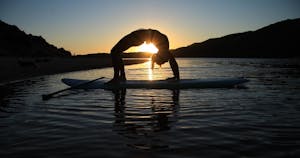 woman doing sup yoga during sunset