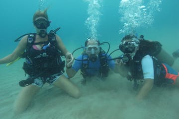 Three scuba divers laying on the bottom of the ocean floor