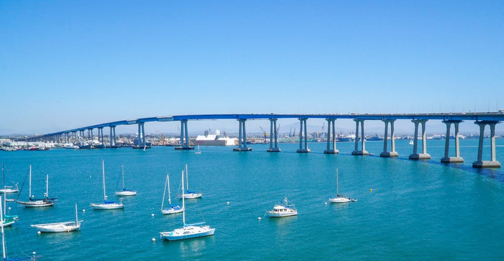 a small boat in a body of water with San Diego–Coronado Bridge in the background