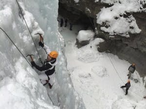 Solo ice climber climbing up cliff