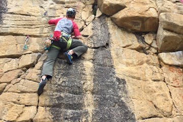 Rock climber climbing up rock wall