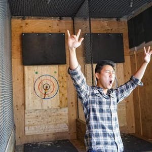 A man celebrates with hands up in the air at Forged Axe throwing