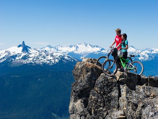 Two mountain bikers pose at the top of whistler mountain