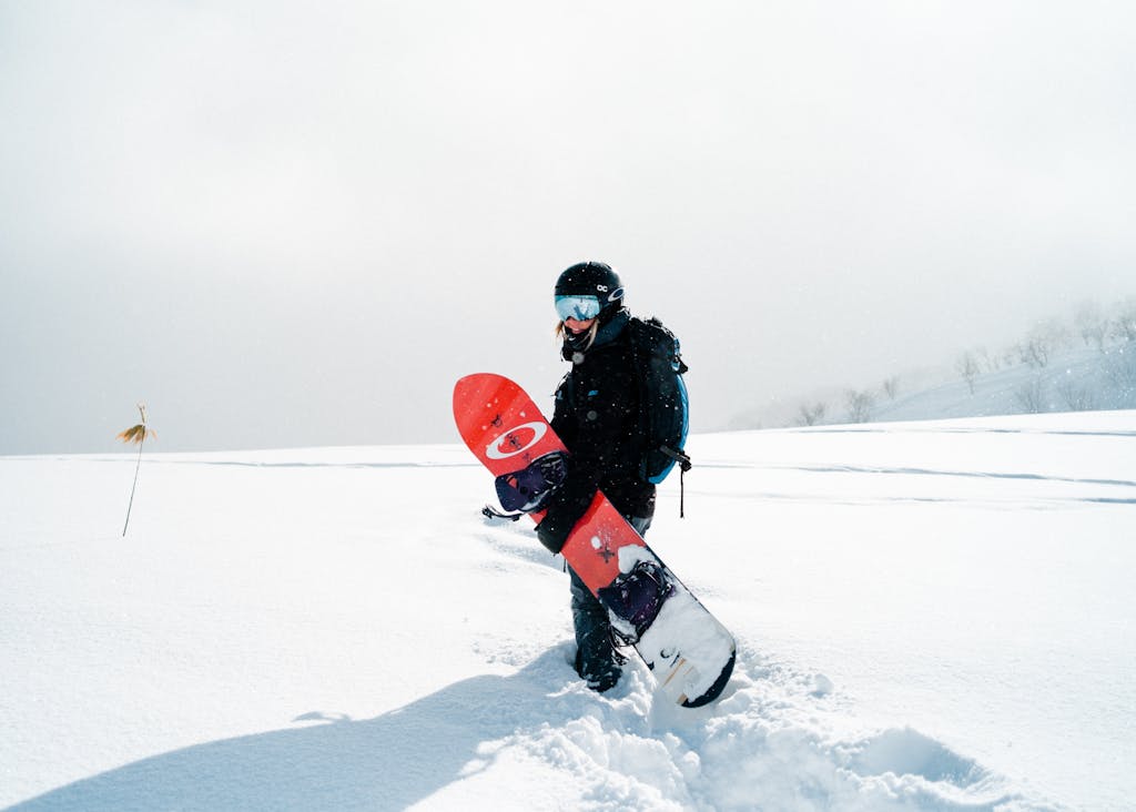 Woman standing in powder with snowboard.