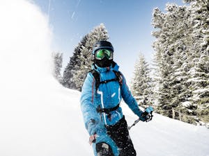 Man skiing with go pro on selfie stick in powder. 
