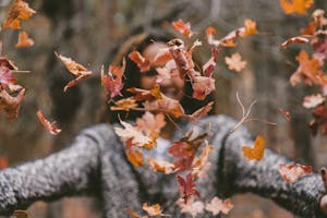 A woman throws leaves into the air, fall season