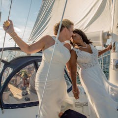 Two women in wedding dresses aboard Moment sailboat