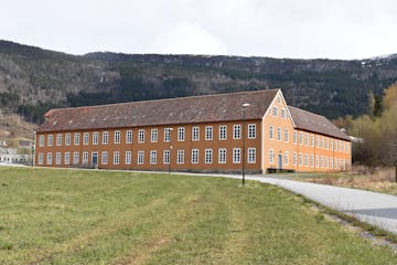 a large brick building with a mountain in the background
