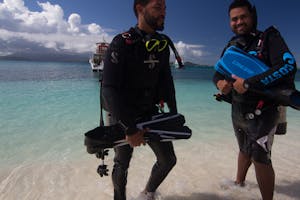 Scuba divers with equipment emerging from the beach