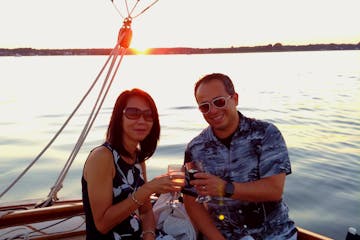 Embrace the romance and beauty of the sunset aboard Sail Selina's private charter in St. Michaels, MD - This stunning image captures the magic of a couple toasting their love story with chilled champagne, surrounded by the breathtaking sunset view - Create unforgettable memories with your partner, book your Sail Selina romantic sunset cruise today!