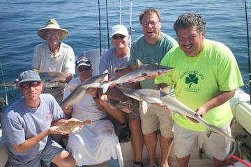 Group holding caught fish on fishing boat
