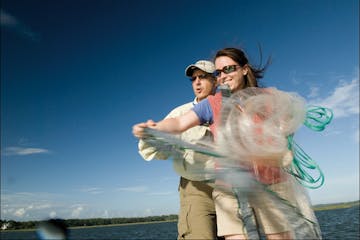 Man showing woman how to throw a casting net