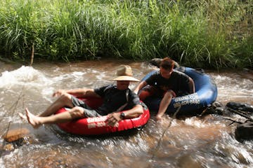 man with sunhat and child sitting in tubes in the river