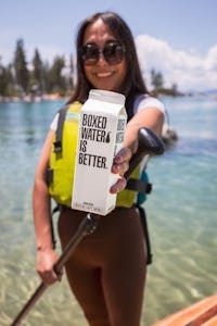 Woman SUP on Lake Tahoe staying hydrated with Boxed Water